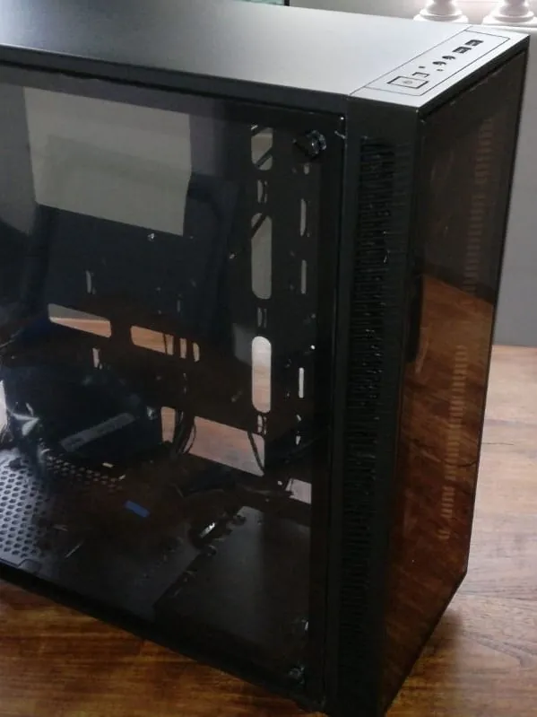 Zwarte pc-behuizing met glazen zijkant op een houten tafel